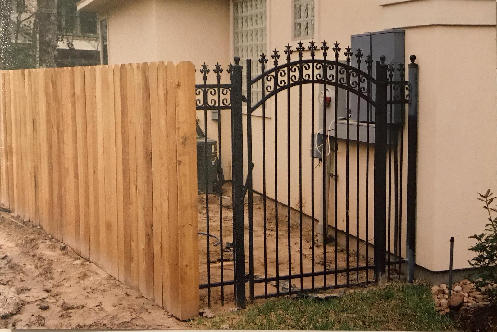Cedar fence with arched steel walk gate, C scrolls and star finials