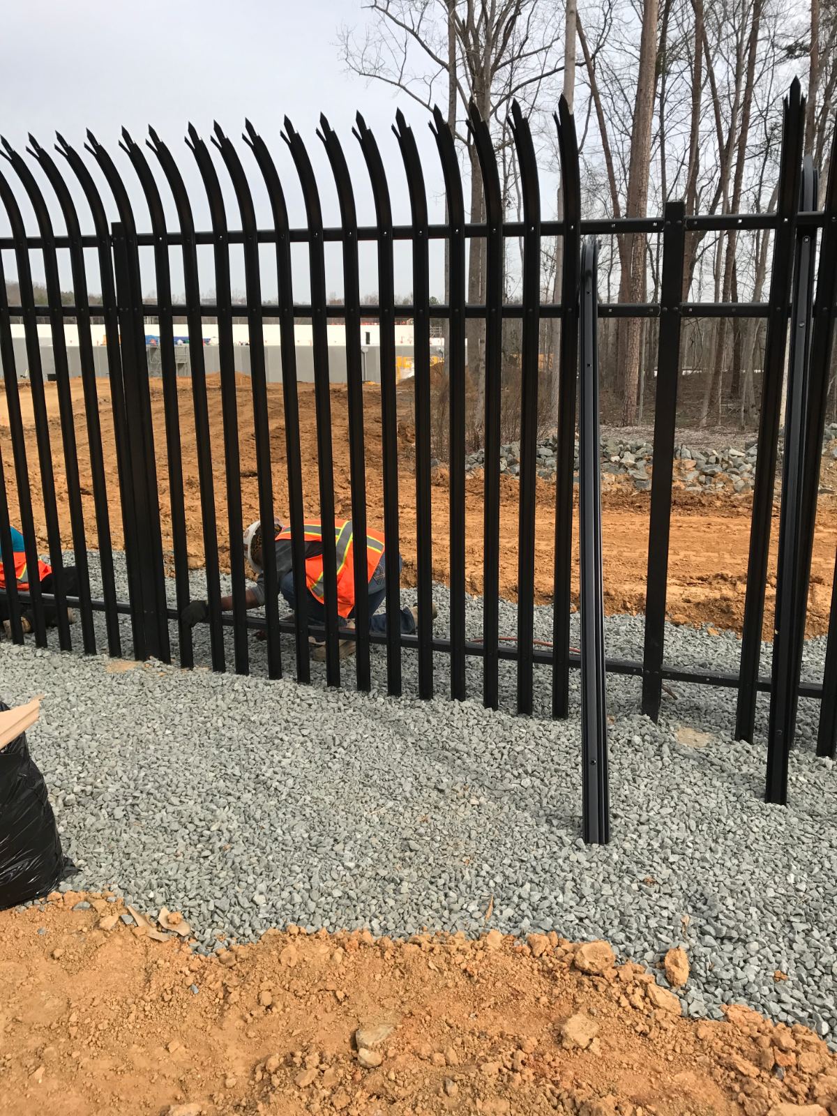 Installation crew securing steel palisade security fence rail at Duke Energy facility