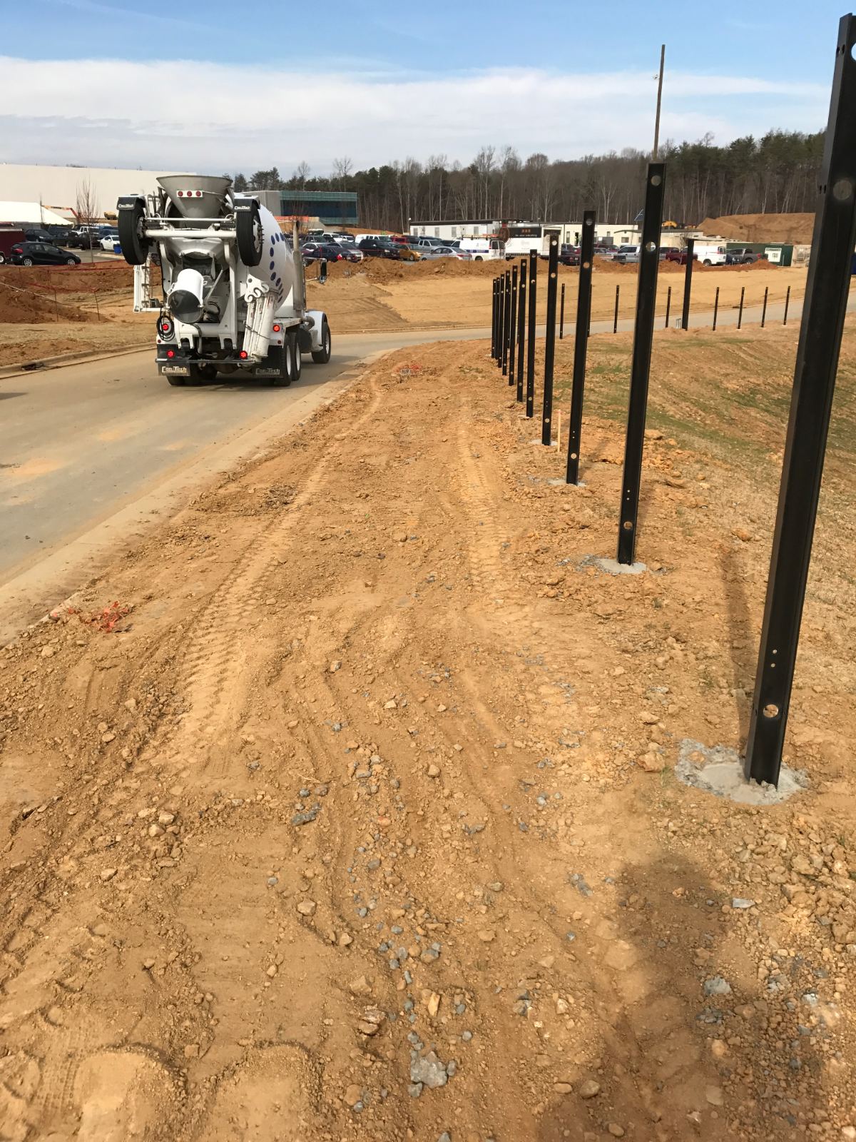 Black steel fence posts set in concrete along roadway during installation at Duke Energy Southeast Command Center, Charlotte NC