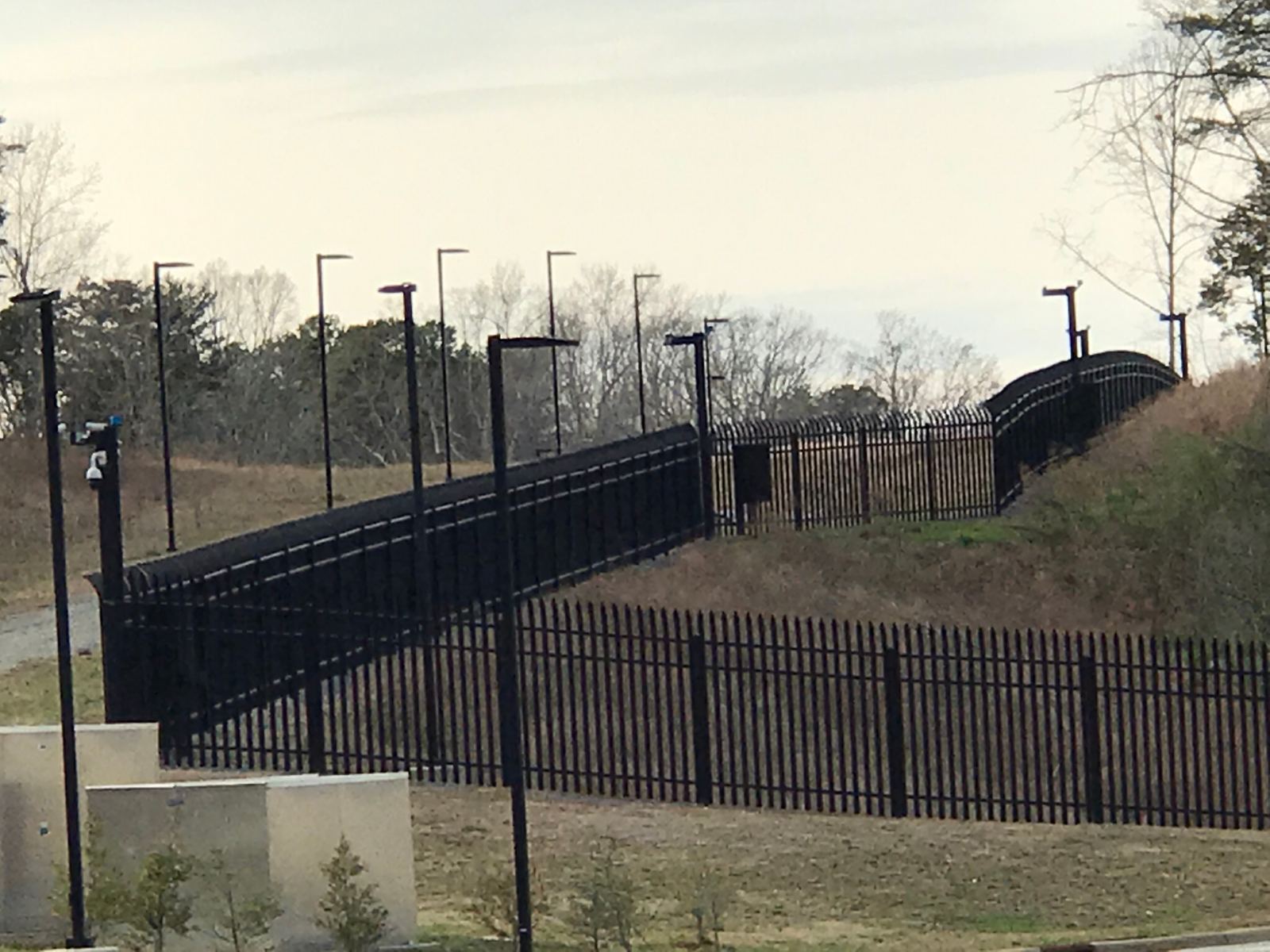 Black ornamental steel perimeter security fence following hillside contour at Duke Energy facility, Charlotte NC