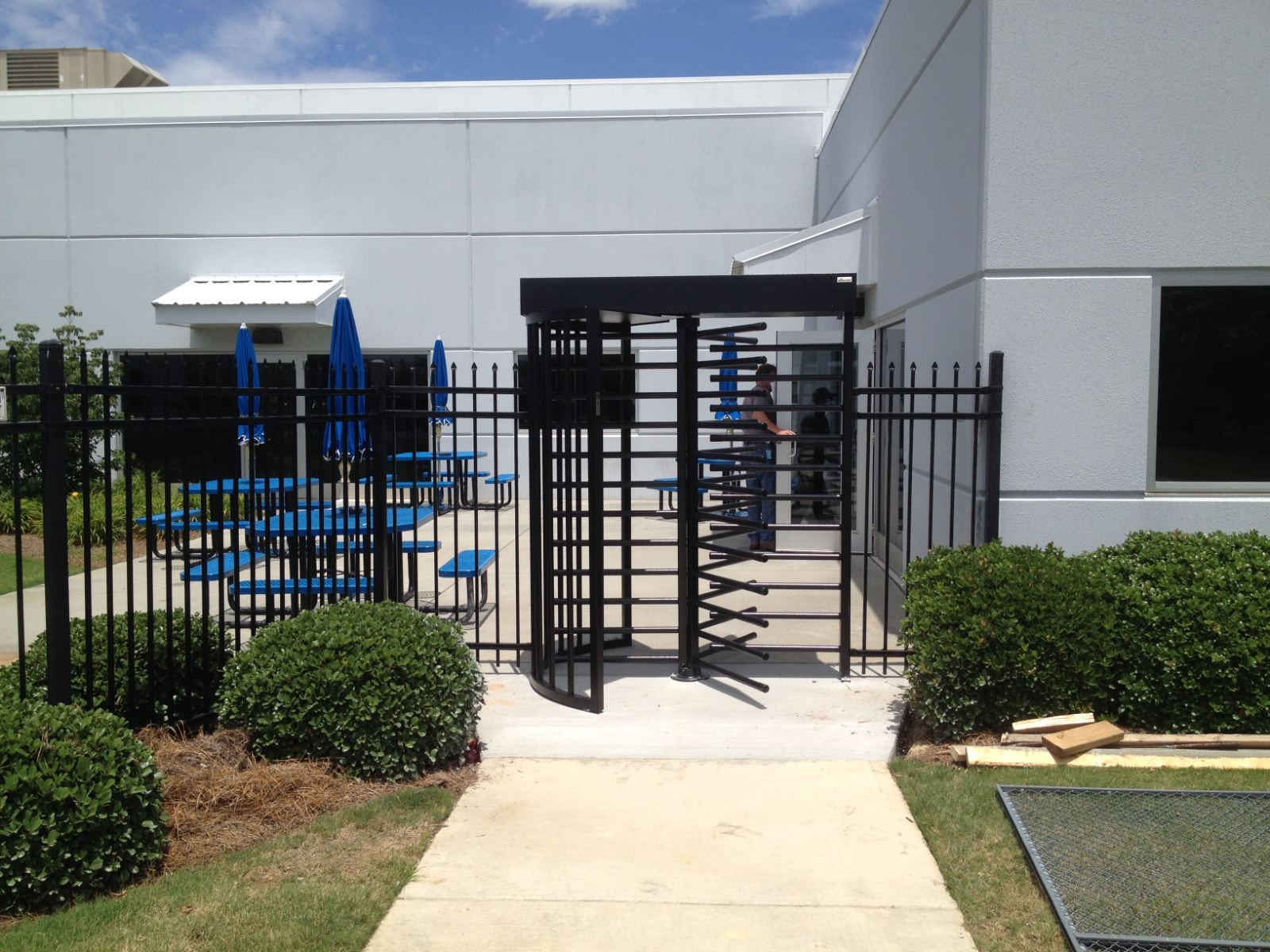 Black powder coated full-height turnstile with 6-foot high 3-rail steel fencing at FedEx facility