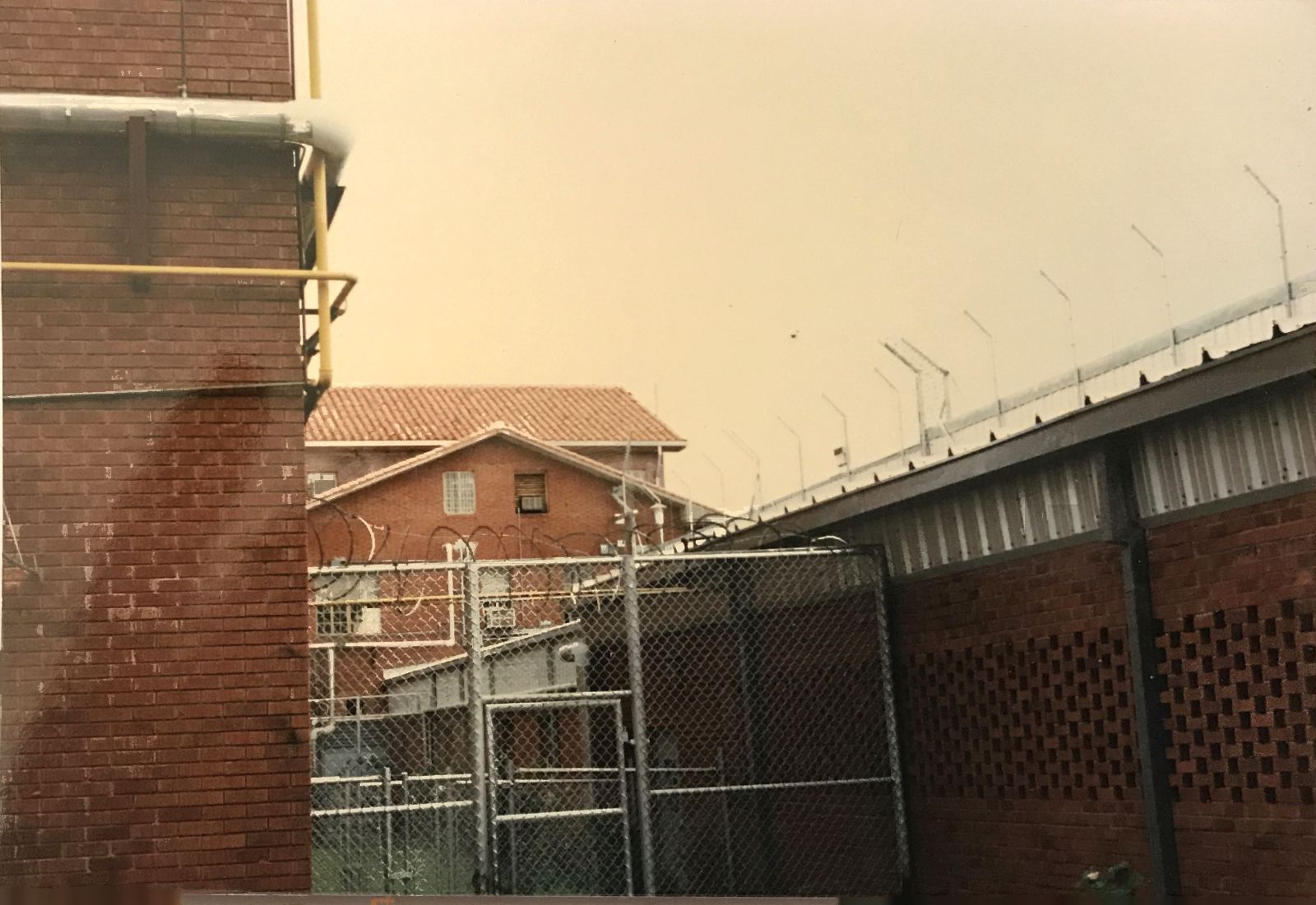 Chain-link security fencing and razor wire beside prison buildings at Huntsville Walls Unit