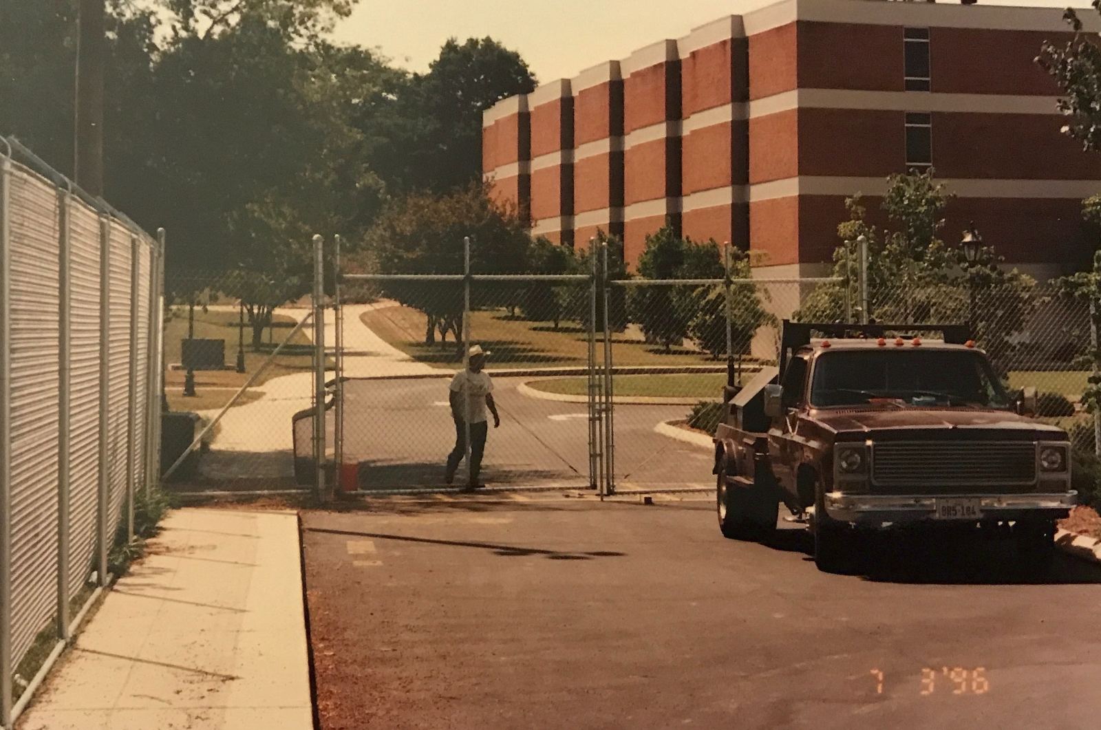 Chain-link security gate with worker and truck at 1996 Olympics satellite site