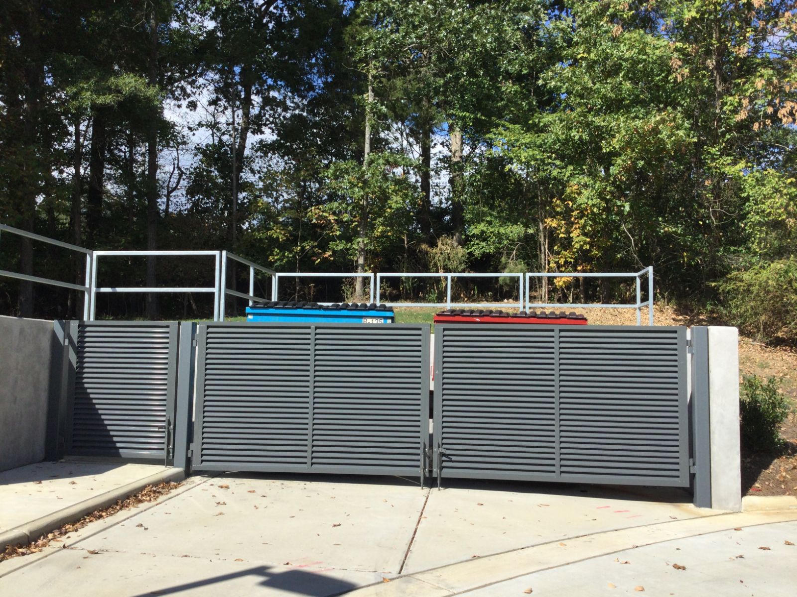 Gray louvered dumpster enclosure gates on steel square tube frame at South Library