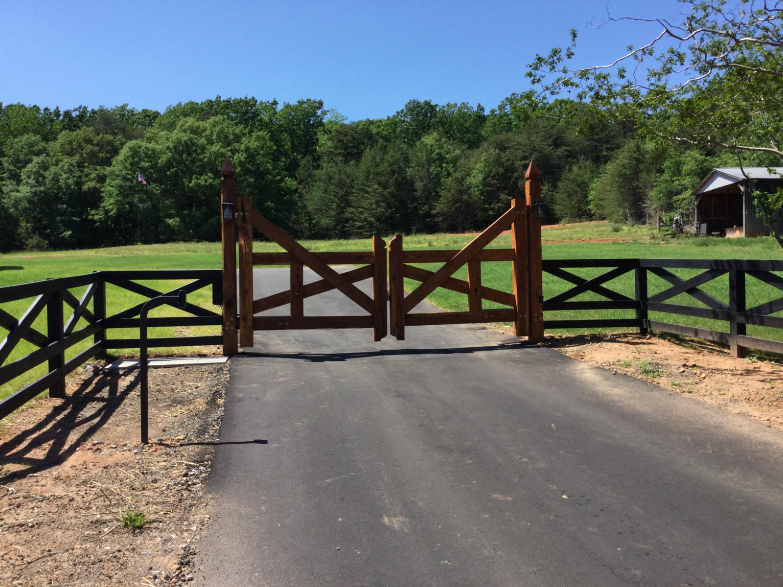 Timber entrance gates with black cross-rail fencing