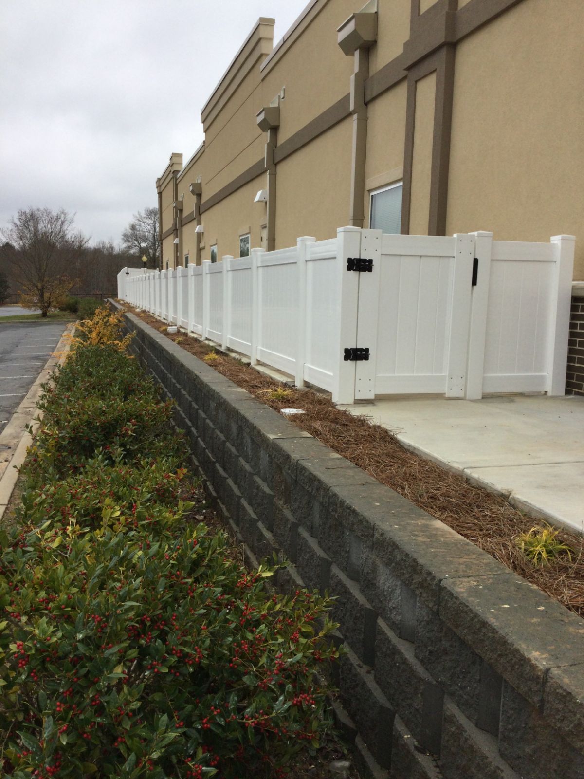 4-foot white PVC fence along building with gate, outside view