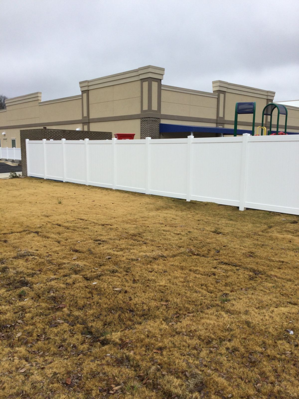 6-foot white vinyl PVC fence around playground looking toward front of building