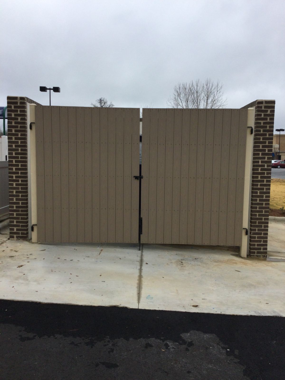Dumpster gates with steel frame and composite boards between brick columns