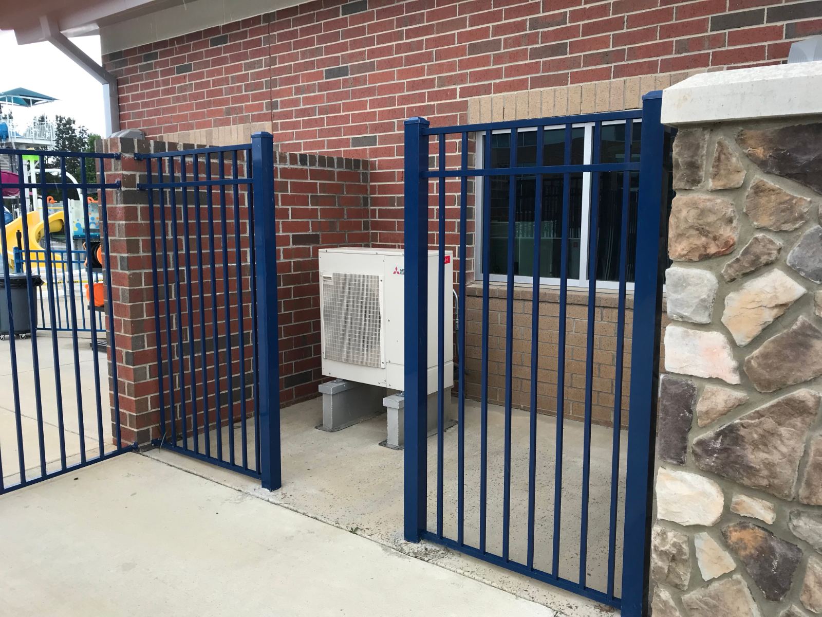 6-foot high blue aluminum fence gate around HVAC unit at YMCA Clover Lake Wylie Aquatics Center
