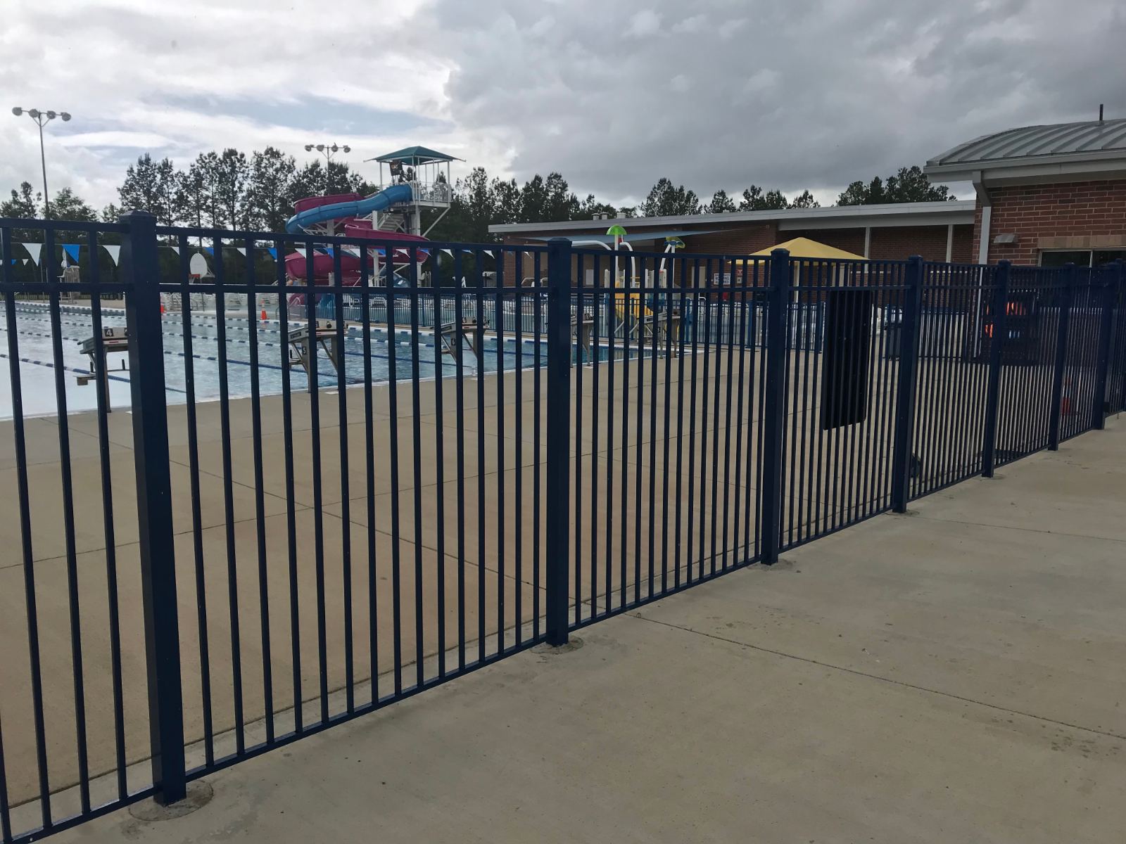 6-foot high blue aluminum fence around outdoor pool deck with water slide at YMCA Clover Lake Wylie Aquatics Center